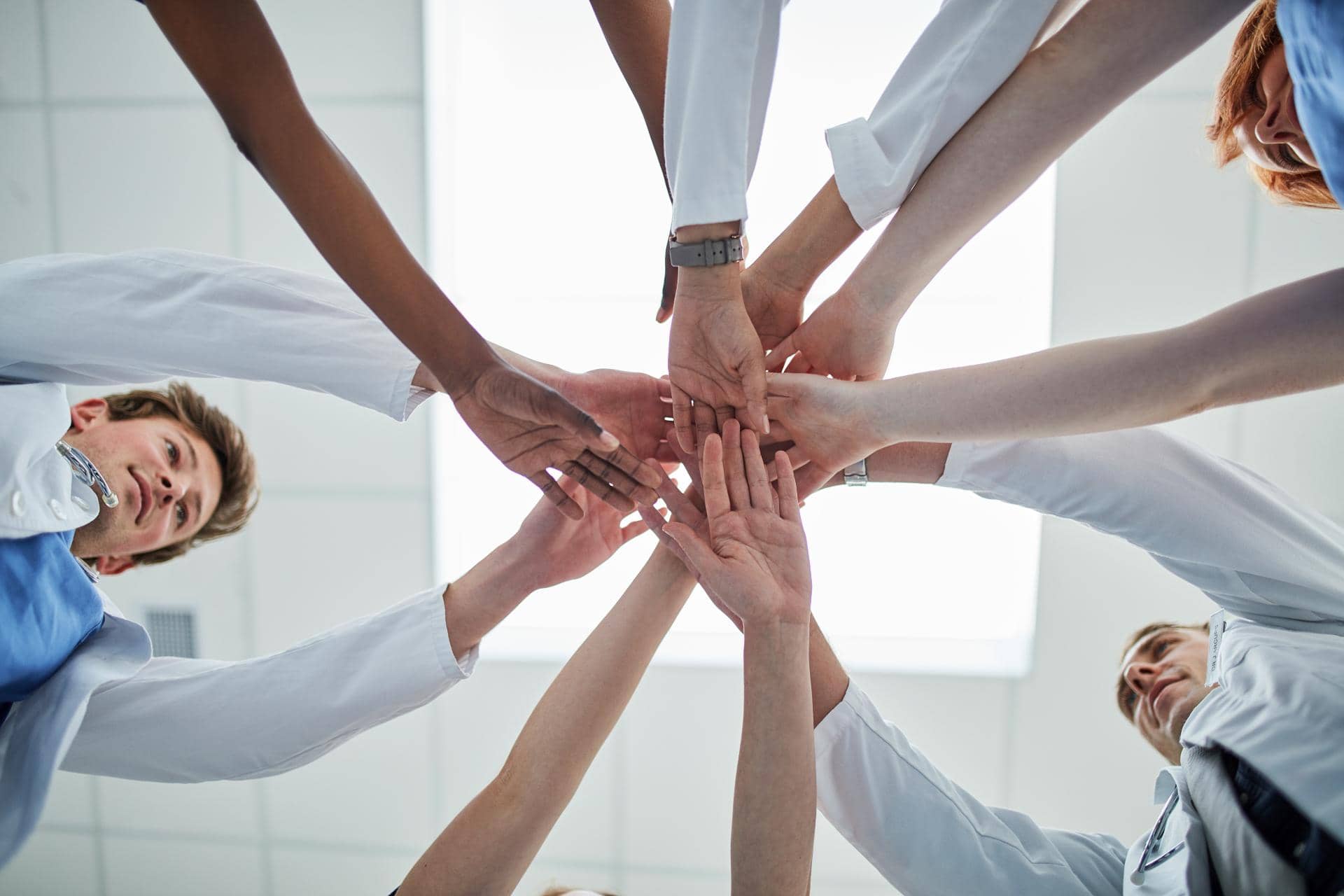 Doctor hands together with team meeting